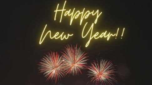 A glowing neon Happy New Year sign above three bursts of fireworks on a dark background.