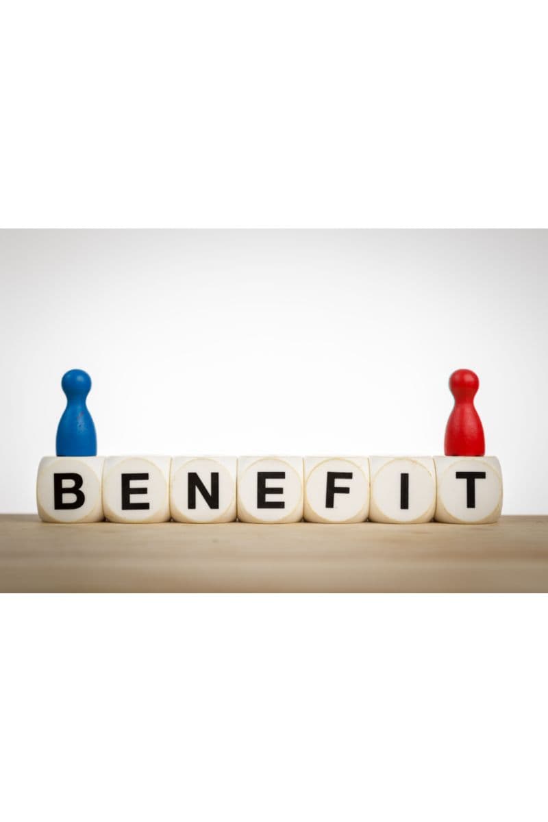 Wooden cubes spelling the word BENEFIT on a table, flanked by a blue and a red game piece.