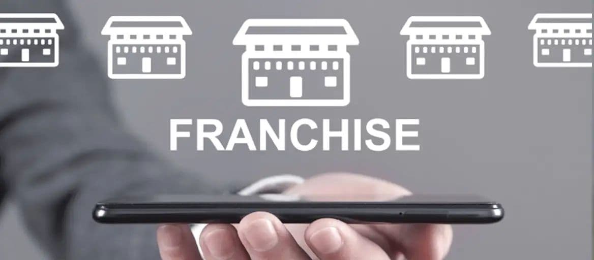 A hand holding a smartphone below the word FRANCHISE and a row of storefront icons.