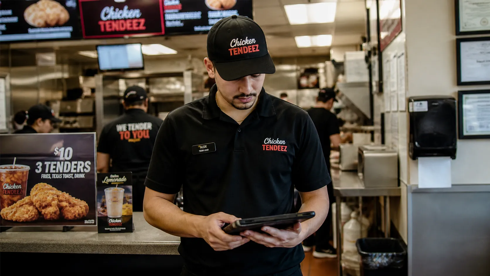 A fast service franchise worker at the front counter completing a checklist on a tablet.