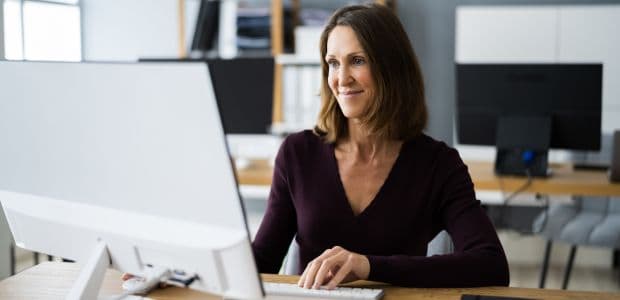 A person working at a desktop computer in a bright office.