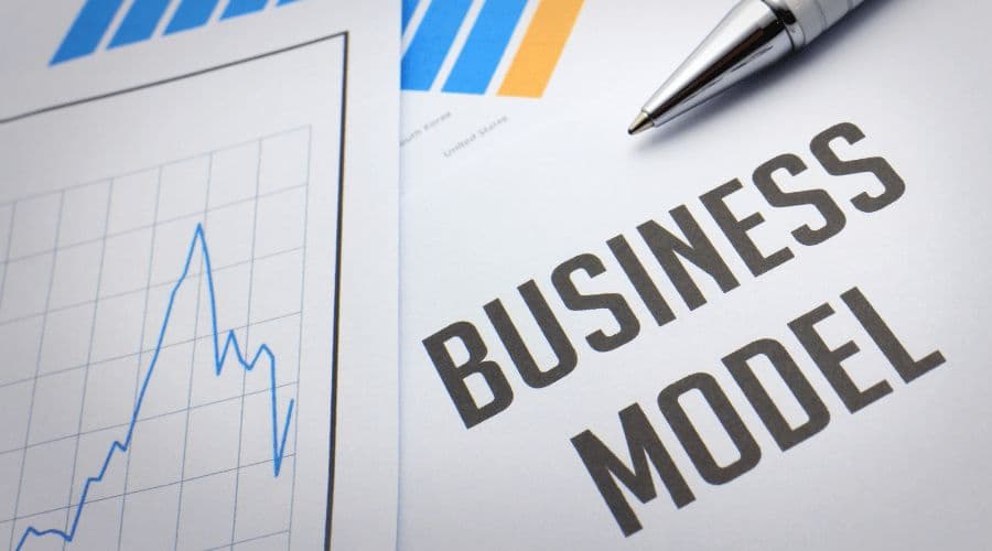 A pen resting on printed business charts next to the words "Business Model".