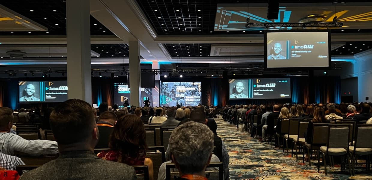 A large conference audience seated facing presentation screens at an industry convention.
