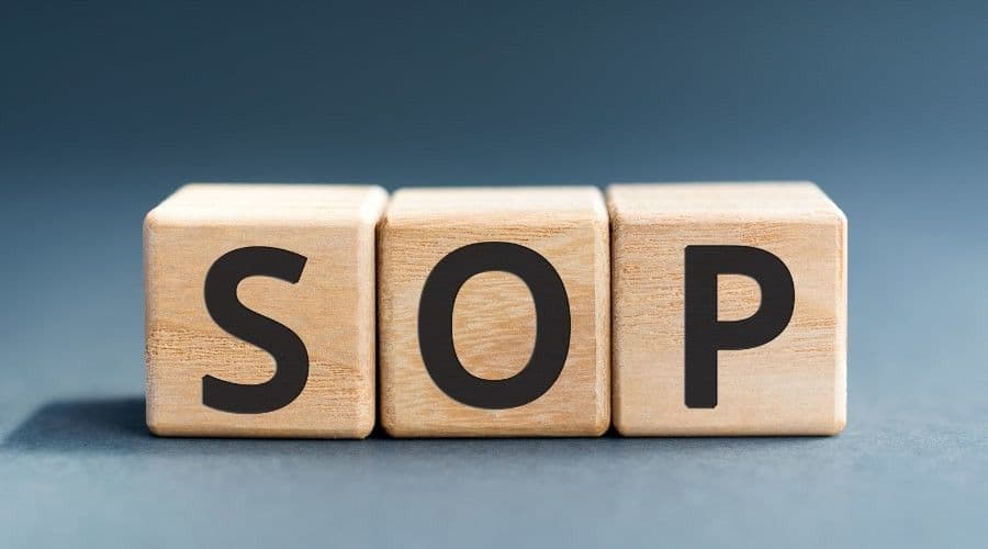 Three wooden blocks on a gray surface spelling out the letters S, O, and P.