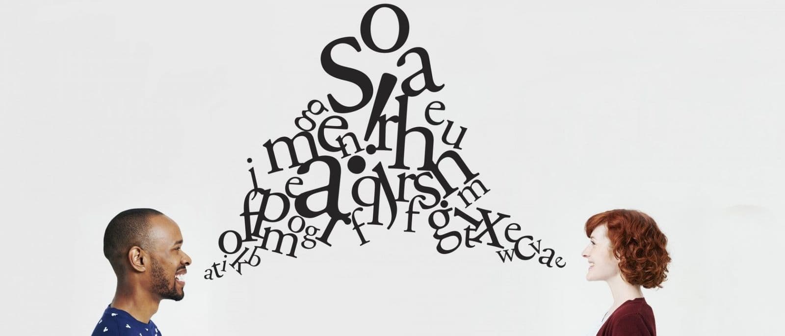 Illustration of a man and a woman facing each other in profile with a jumble of black letters floating between them, representing communication.