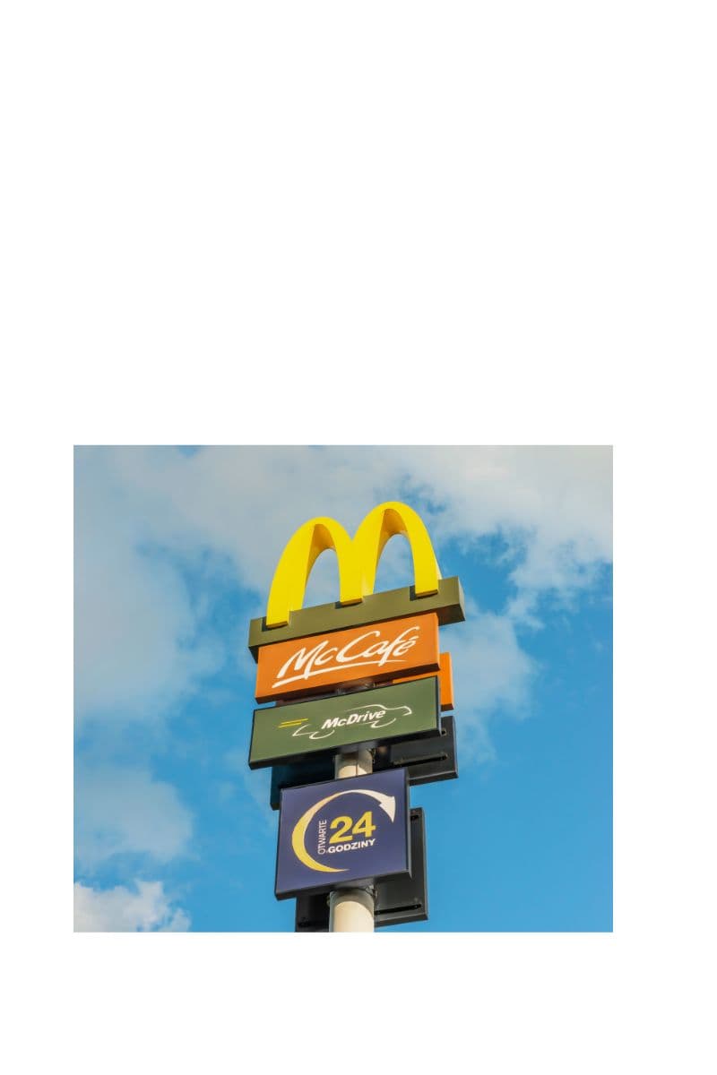 A roadside McDonald's pole sign with the golden arches, McCafe, and McDrive panels against a blue sky.