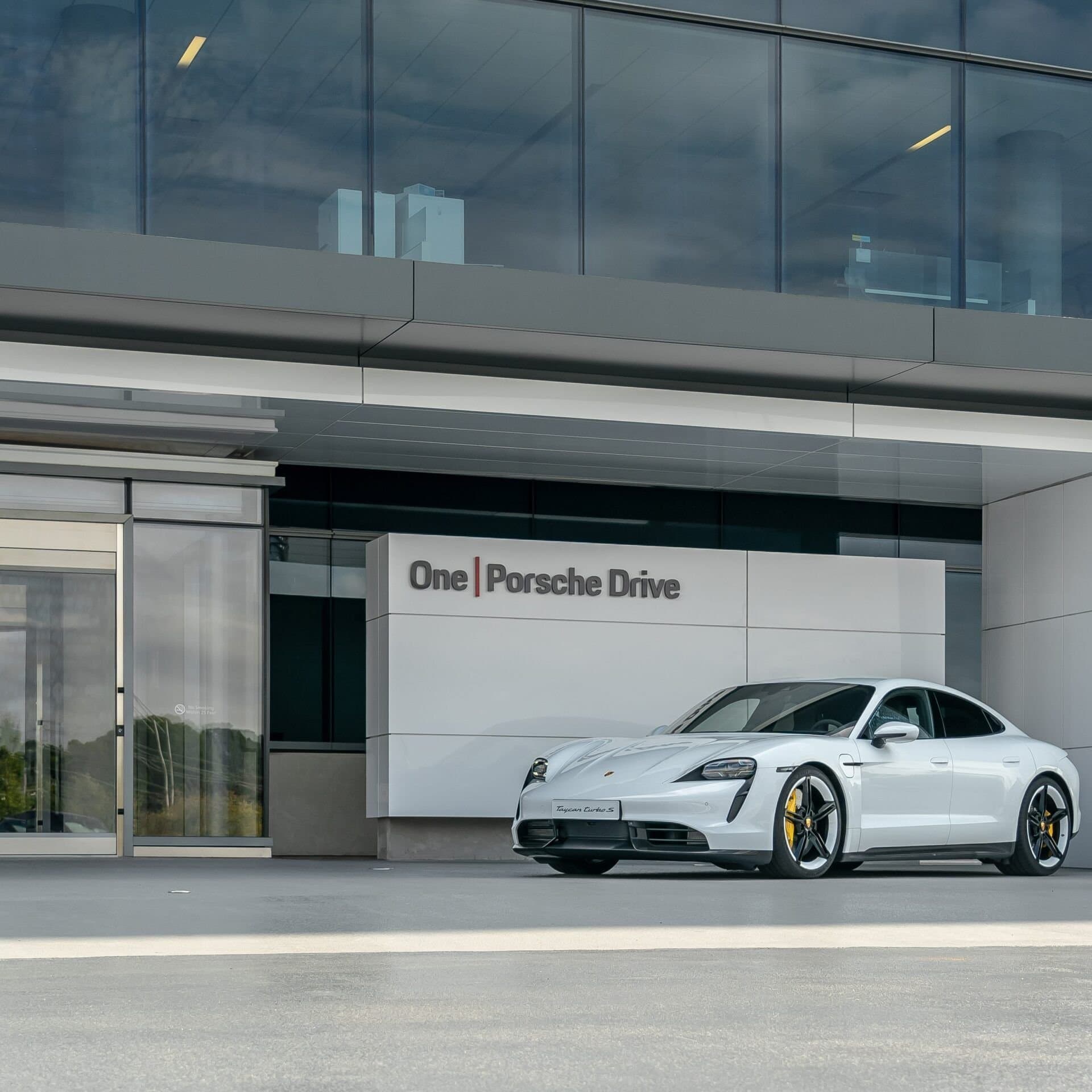 A white Porsche Taycan Turbo S parked outside the One Porsche Drive entrance in Atlanta