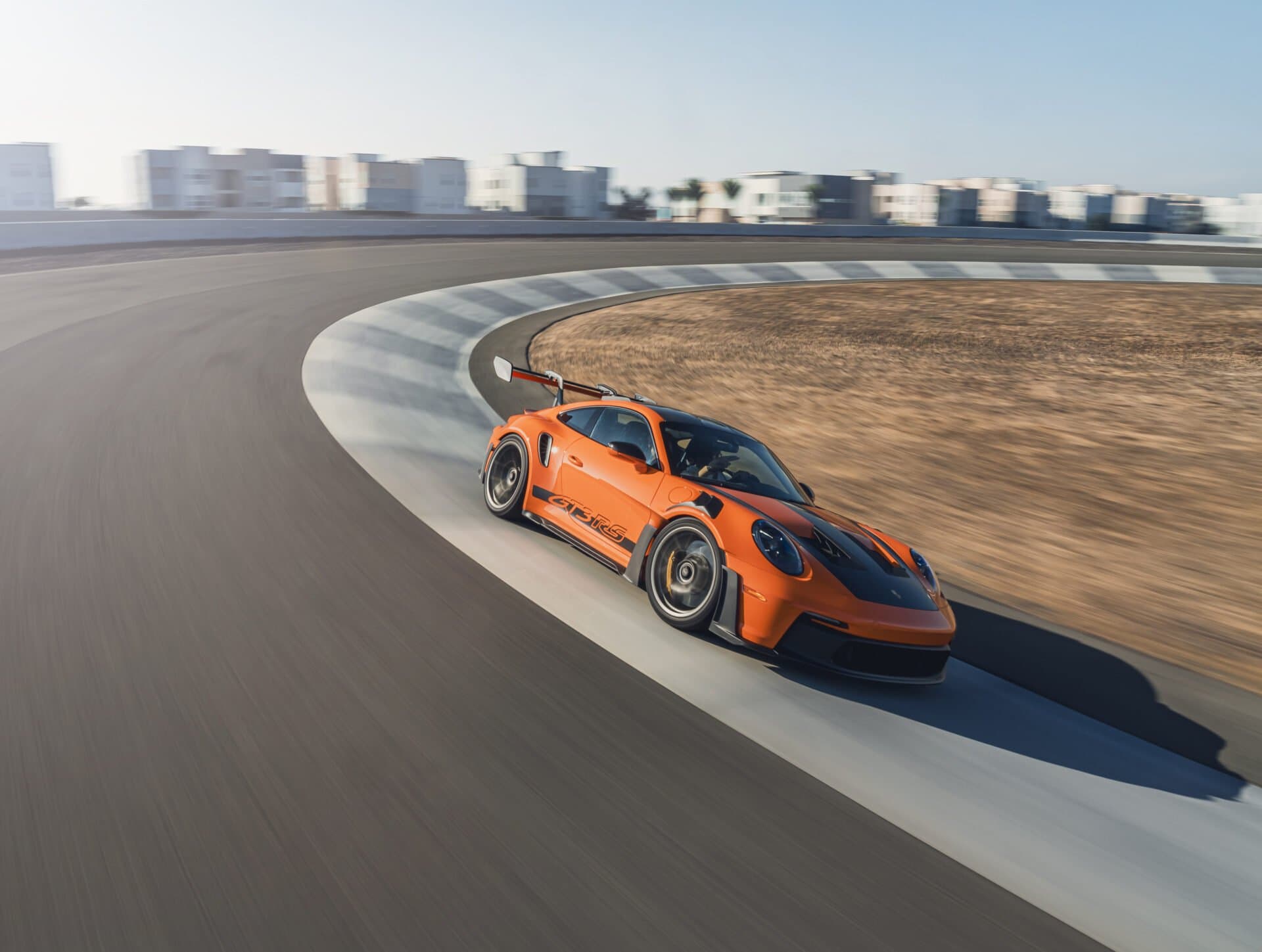 An orange Porsche 911 GT3 RS cornering on a racetrack