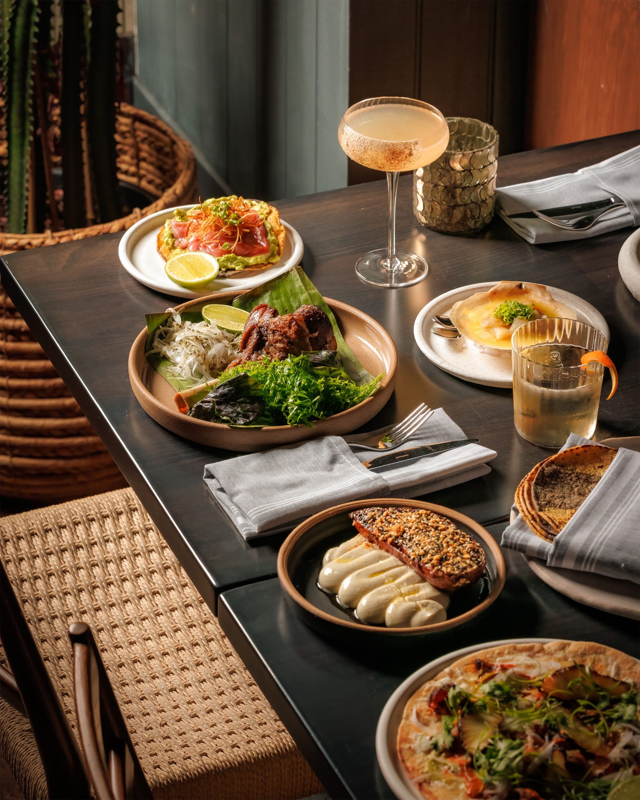 A set table at Alteño with shared plates and cocktails