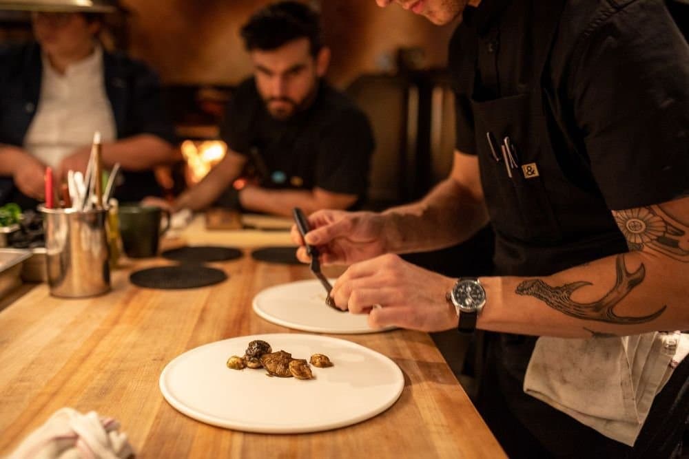A chef plating a course at the kitchen counter at Hestia
